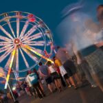 people wating in line at the amusement park to get on the rides